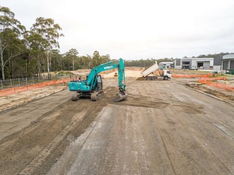 Excavator grading a commercial building pad on an industrial estate